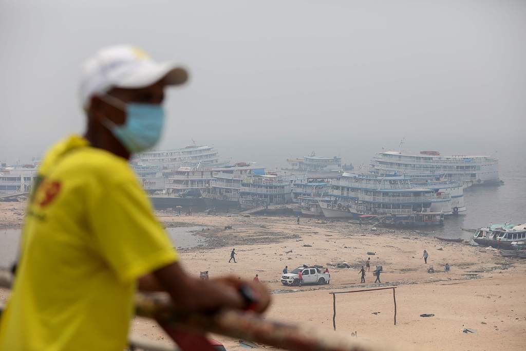 A man wearing a facemask observes boats anchored in Rio Negro port as smoke haze from fires in the Amazon rainforest blankets the area in Manaus, Brazil, October 13, 2023. /CFP