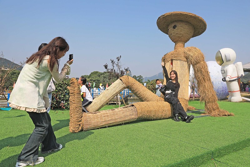 Visitors take photos with artistic scarecrow installations in Zhoushan City, Zhejiang Province, October 15, 2023. /CFP