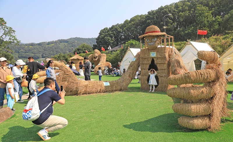 Visitors take photos with artistic scarecrow installations in Zhoushan City, Zhejiang Province, October 15, 2023. /CFP