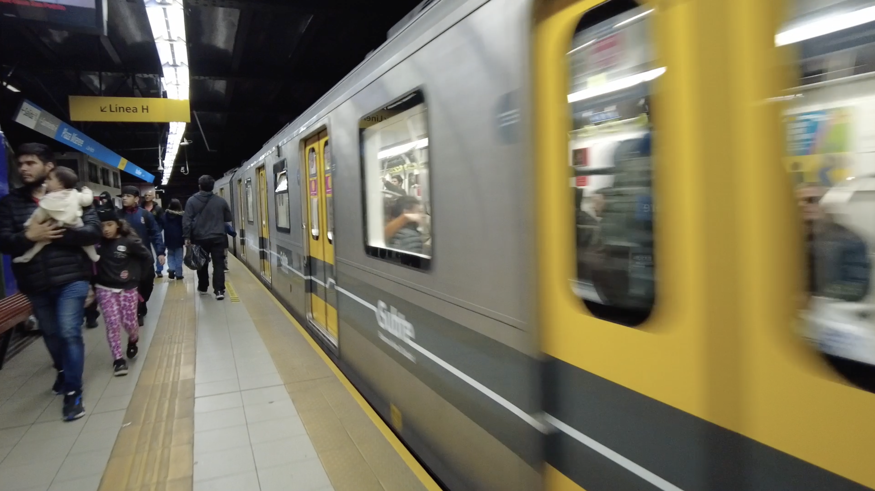 A lithium battery-powered train built by CRRC zips past commuters on a metro station platform in Buenos Aires. /CGTN