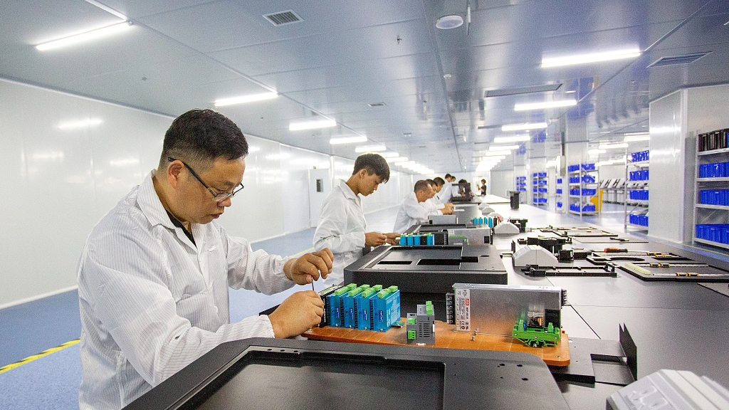 Workers fine-tuning newly installed high-tech machinery, in a workshop located in Fuzhou, Jiangxi Province, China. /CFP