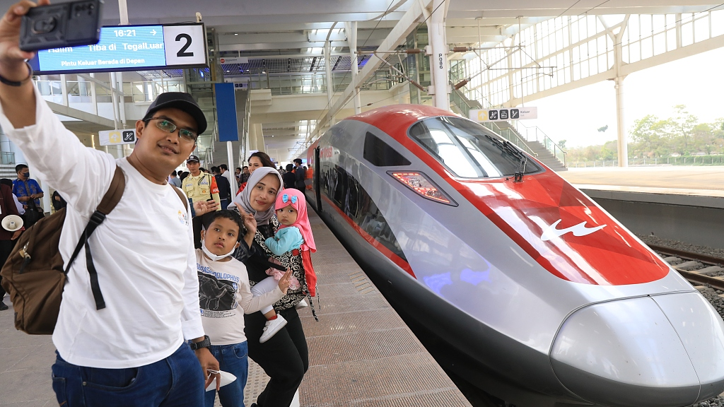 A family takes a group photo in front of a train of Jakarta-Bandung HSR at Halim Station in Jakarta, Indonesia, October 17, 2023. /CFP