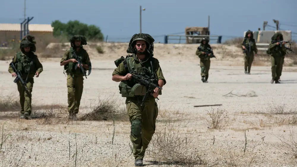 Israeli soldiers walk near the border with the central Gaza Strip, July 14, 2014. /Reuters