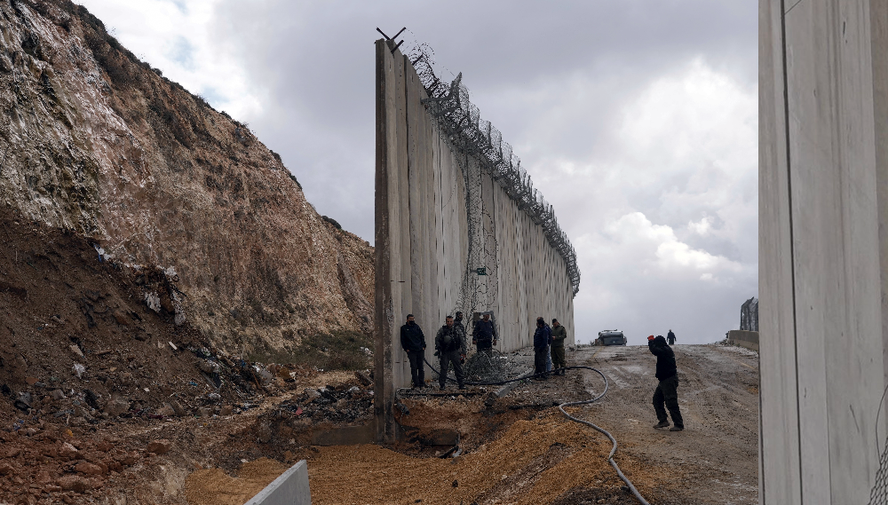 Workers rebuild a section of Israel's separation barrier after a part of it collapsed between Jerusalem and the West Bank village of A-Ram, February 6, 2022. /AP