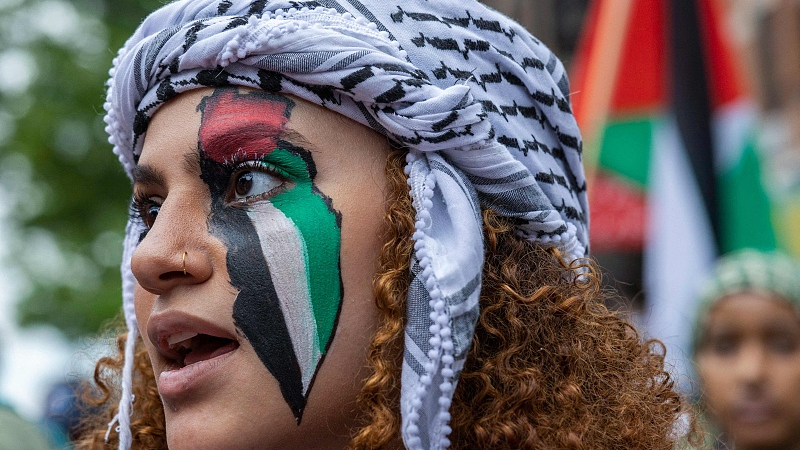 A Palestine rights supporter wears the colors of the Palestinian flag painted on her face during a march to mark the 75th anniversary of Nakba, or the 