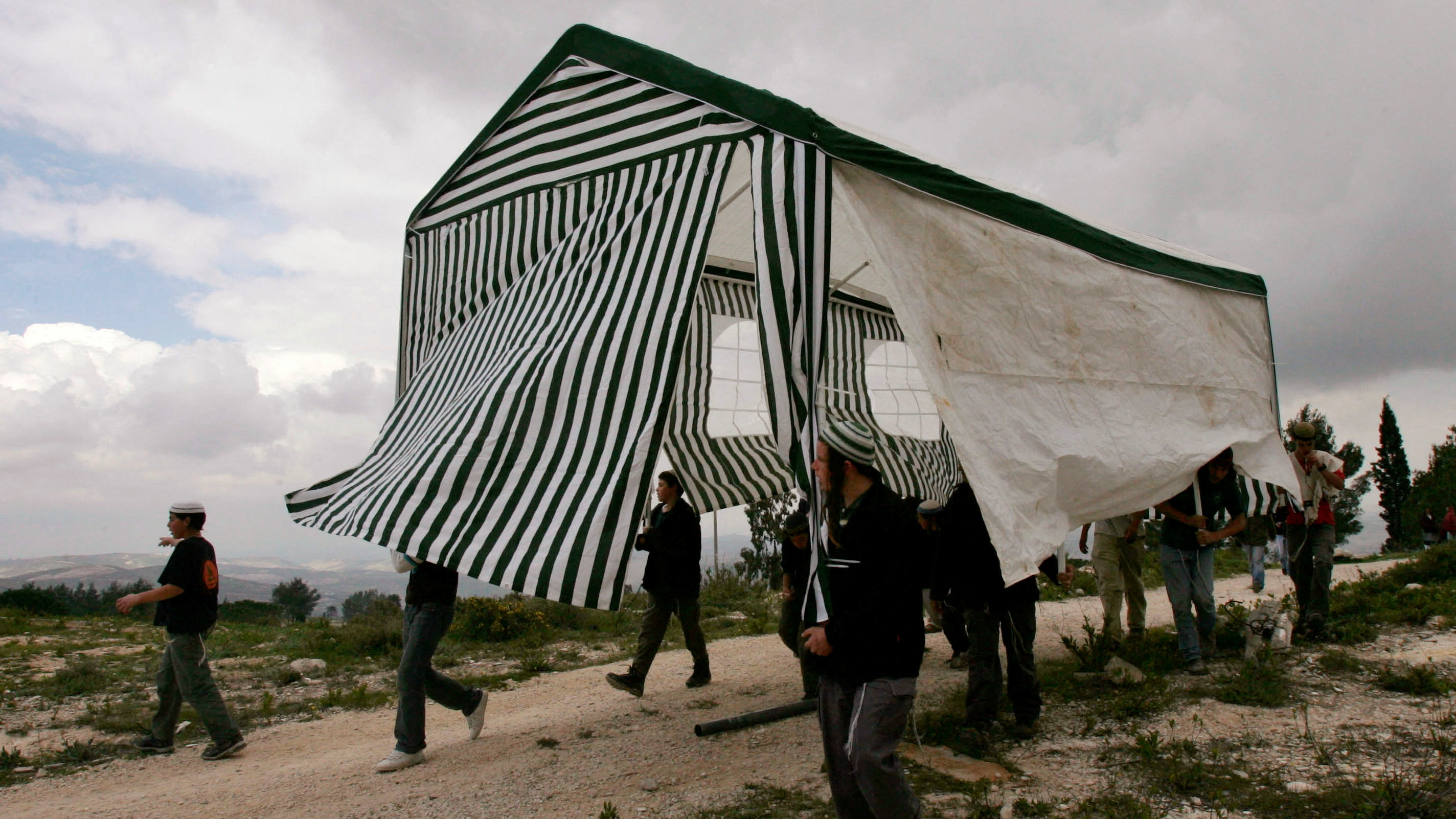 Israeli activists carry a tent in the abandoned Jewish settlement of Homesh, in the northern West Bank, March 27, 2007. /Reuters