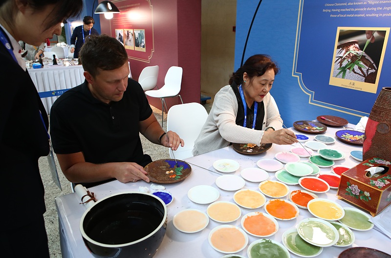 Journalists paint patterns on plates at the media center for the third Belt and Road Forum for International Cooperation in Beijing on October 17, 2023. /CFP