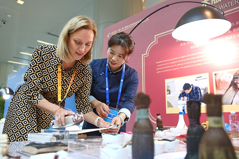 An international journalist experiences traditional Chinese craft skills at the media center for the third Belt and Road Forum for International Cooperation in Beijing, October 17, 2023. /CFP