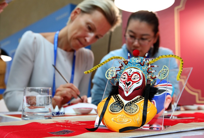 An international journalist paints on masks at the media center for the third Belt and Road Forum for International Cooperation in Beijing, October 17, 2023. /CFP