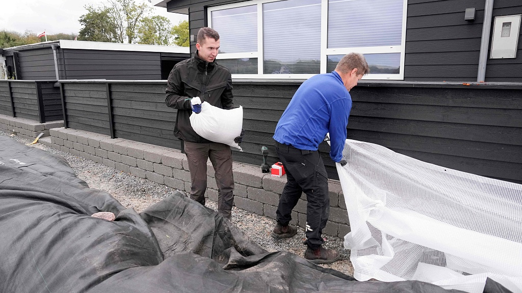 Jacob Nissen and Christian Mikkelsen (R) secure their summer house with sandbags at Sonderballe Strand near Haderslev after a weather warning was issued for the area, southern Denmark, October 19, 2023. /CFP