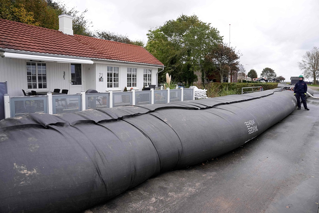 A member of the Danish Emergency Management Agency stands next to an AquaDam flood barrier as measures are taken to protect against damage from flood water at Sonderballe Strand near Haderslev, southern Denmark, October 19, 2023