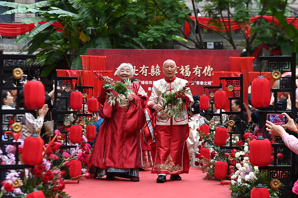 Photo shows an elderly couple walking down the aisle wearing traditional Chinese wedding attire in Chongqing, October 19, 2023. /CFP