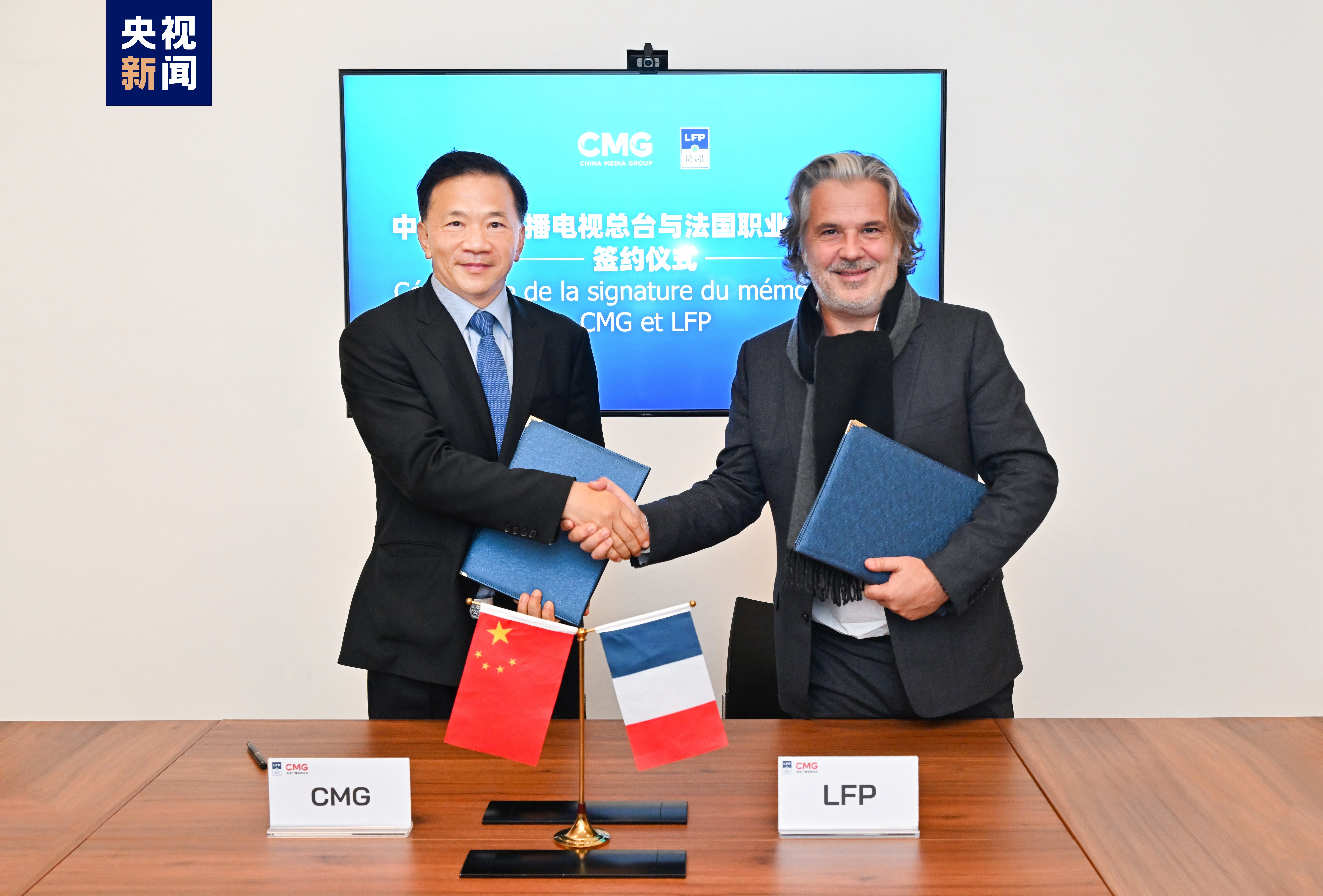 Shen Haixiong (L), president of China Media Group, and Vincent Labrune, president of France's Ligue de Football Professionnel, shake hands after signing a memorandum of cooperation, October 23, 2023. /CMG