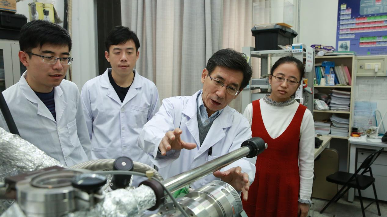 Chinese physicist Xue Qikun (2nd R) with his students in the lab. /Tsinghua University