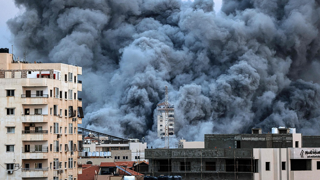 A plume of smoke rises above buildings in Gaza City on October 7, 2023 during an air strike./CFP