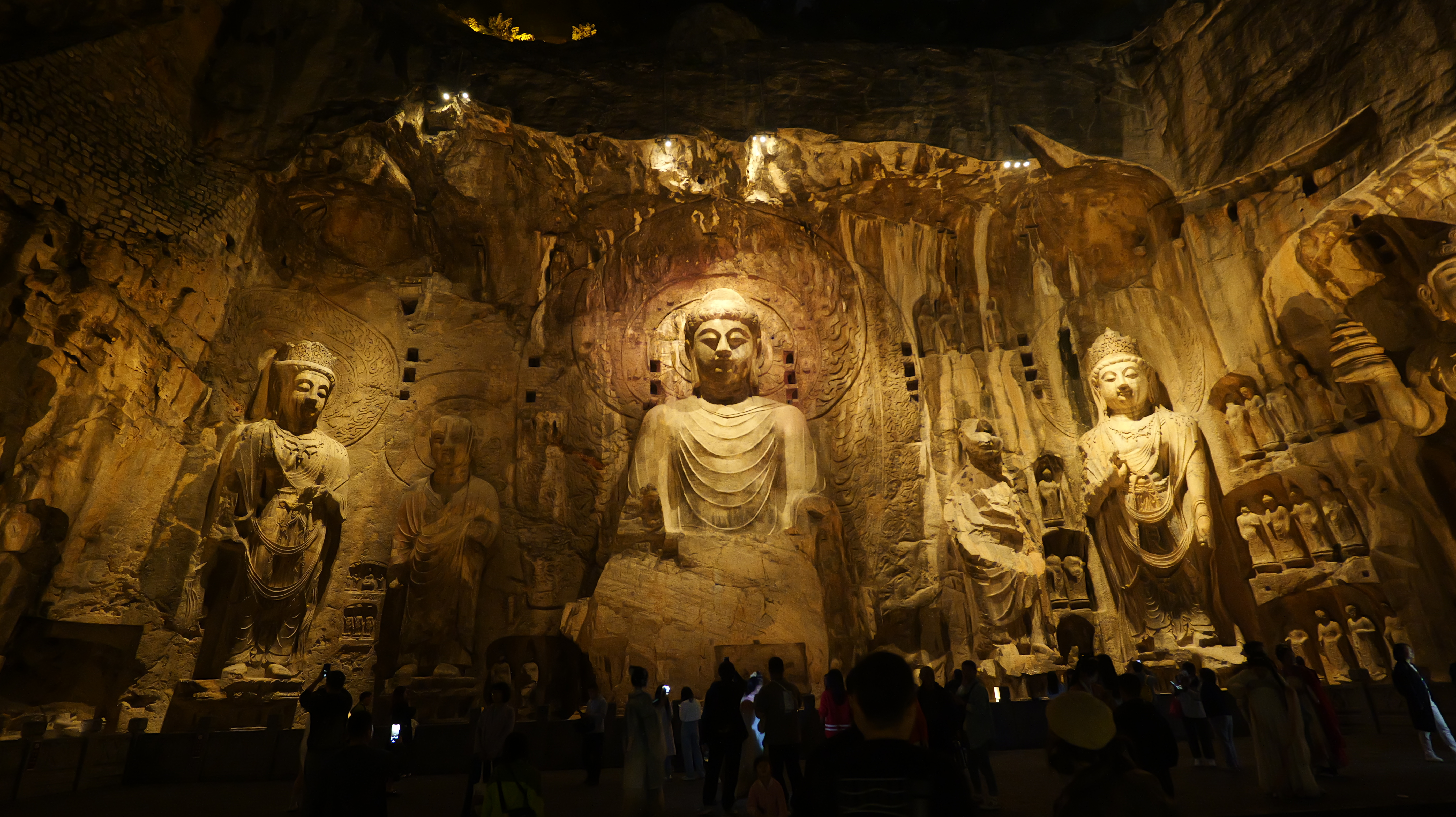 Visitors crowd in front of the Buddha statues at the Longmen Grottoes in Luoyang, central China's Henan Province on October 26, 2023, as it opens night tours to the visitors. /IC 