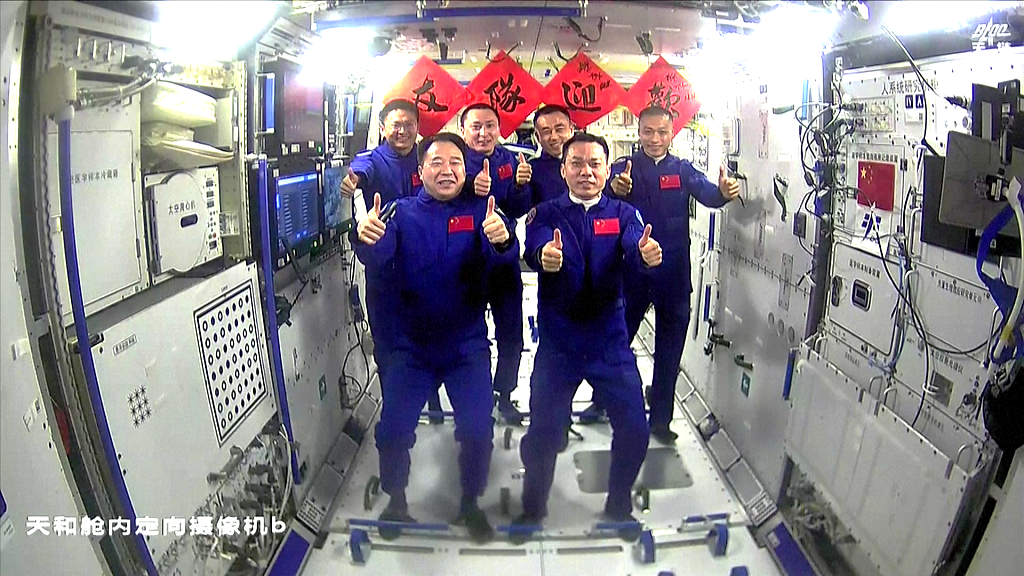 A group photo of the Shenzhou-16 and the Shenzhou-17 crew members, with a banner saying 