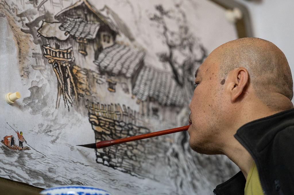 Huang Guofu paints with a brush in his mouth at his studio in Chongqing. /CFP