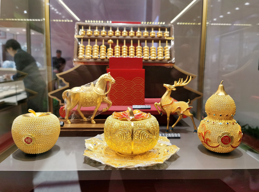 Gold ornaments in the shapes of an apple, horse, persimmon, deer and gourd (from left to right) at the 2023 China International Jewelry Fair in Beijing are seen in this photo taken on October 26, 2023. /CFP