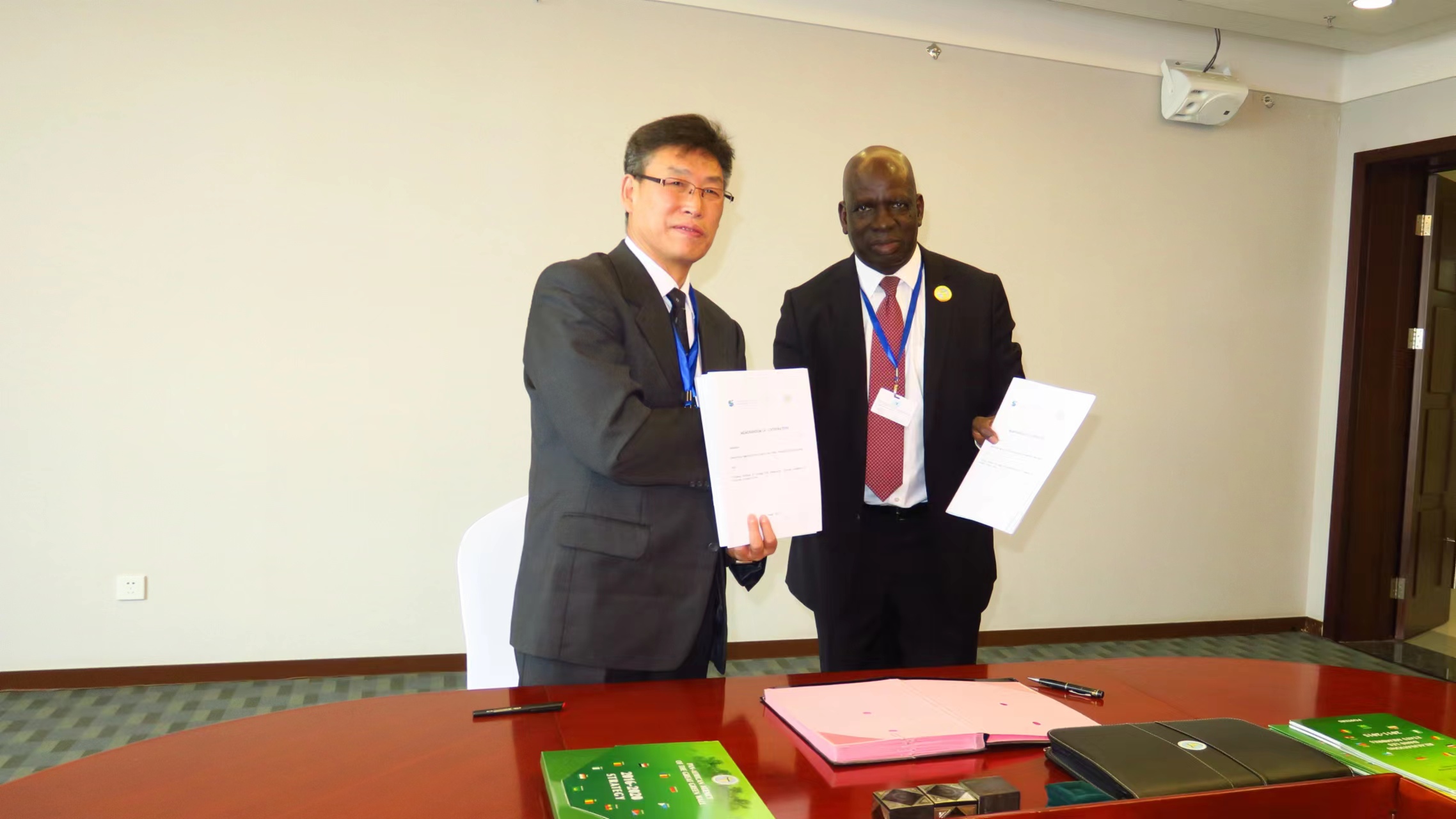 Lei Jiaqiang (L), on behalf of the Xinjiang Institute of Ecology and Geography, Chinese Academy of Sciences, signs a memorandum of cooperation with Abdoulaye Dia, the then executive secretary of the Pan-African Agency of the Great Green Wall, in Erdos, north China's Inner Mongolia Autonomous Region, September 15, 2017. /Courtesy of Lei Jiaqiang