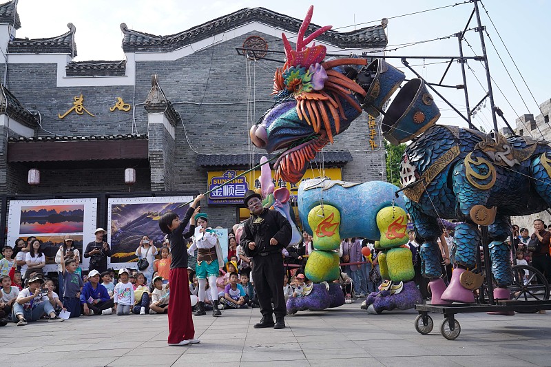 A boy interacts with a puppet of a mythical creature on East West Street in Guilin City, Guangxi Zhuang Autonomous Region, October 28, 2023. /CFP