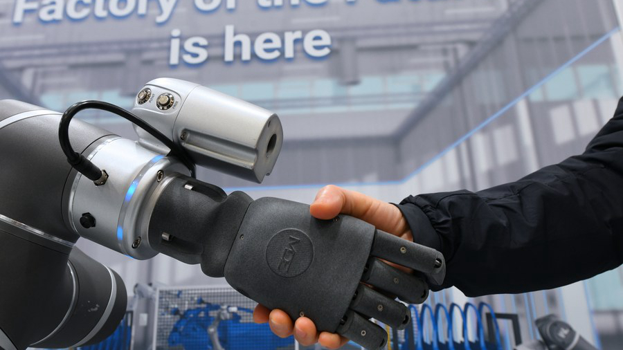 A visitor shakes hands with an intelligent robot at Hannover Messe 2023 in Hannover, Germany, April 19, 2023. /Xinhua
