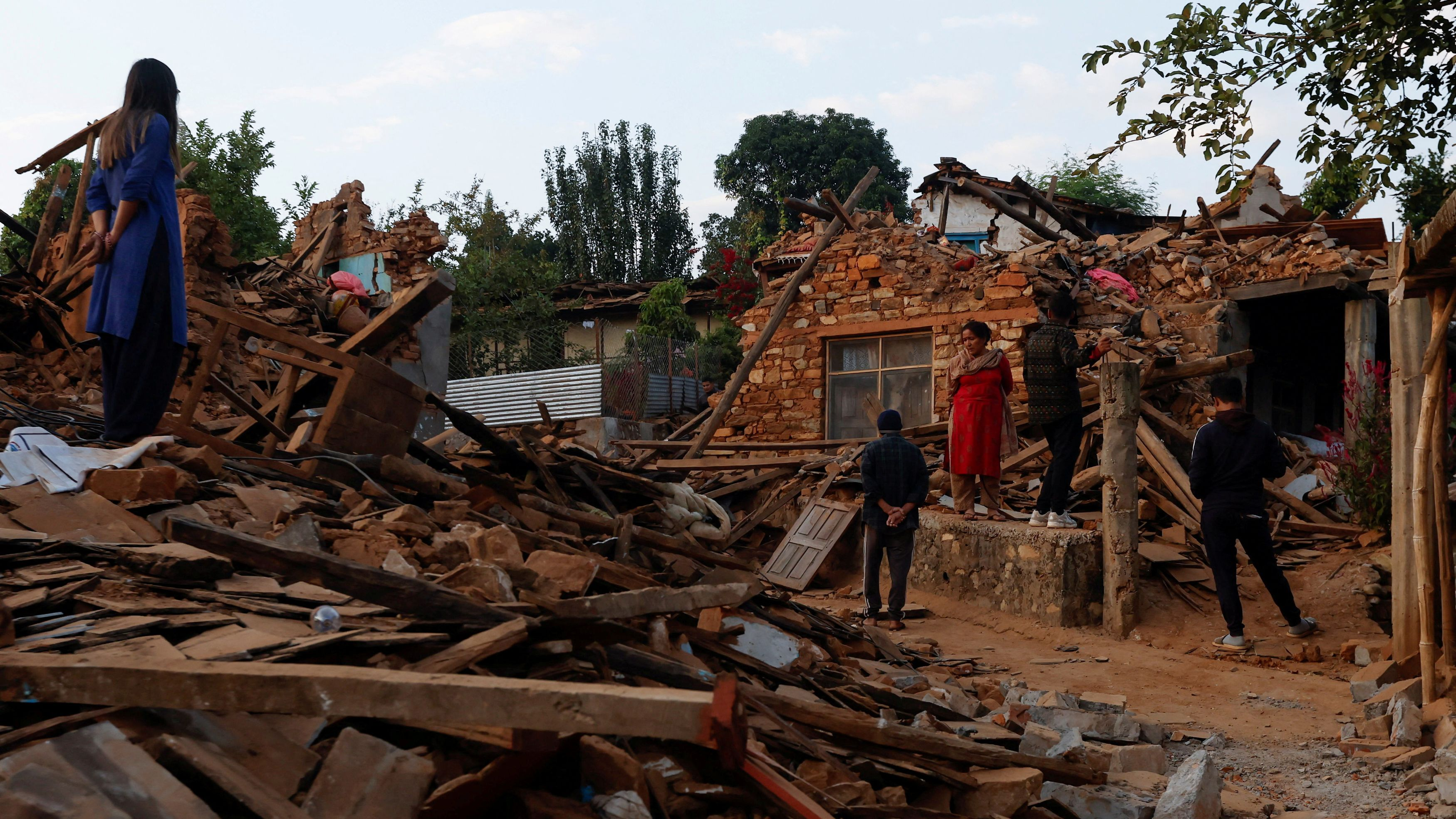 People stand outside the remnants of collapsed houses after an earthquake in Jajarkot, Nepal, November 5, 2023. /Reuters