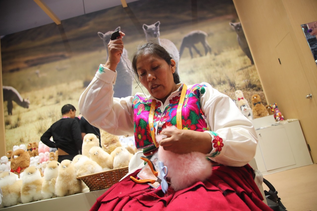 A photo taken on November 5, 2023, shows a Peruvian artisan making stuffed vicuna toys from Peru at the CIIE, Shanghai, China. /CFP