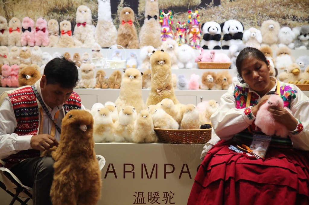 A photo taken on November 5, 2023, shows Peruvian artisans making stuffed vicuna toys from Peru at the CIIE, Shanghai, China. /CFP