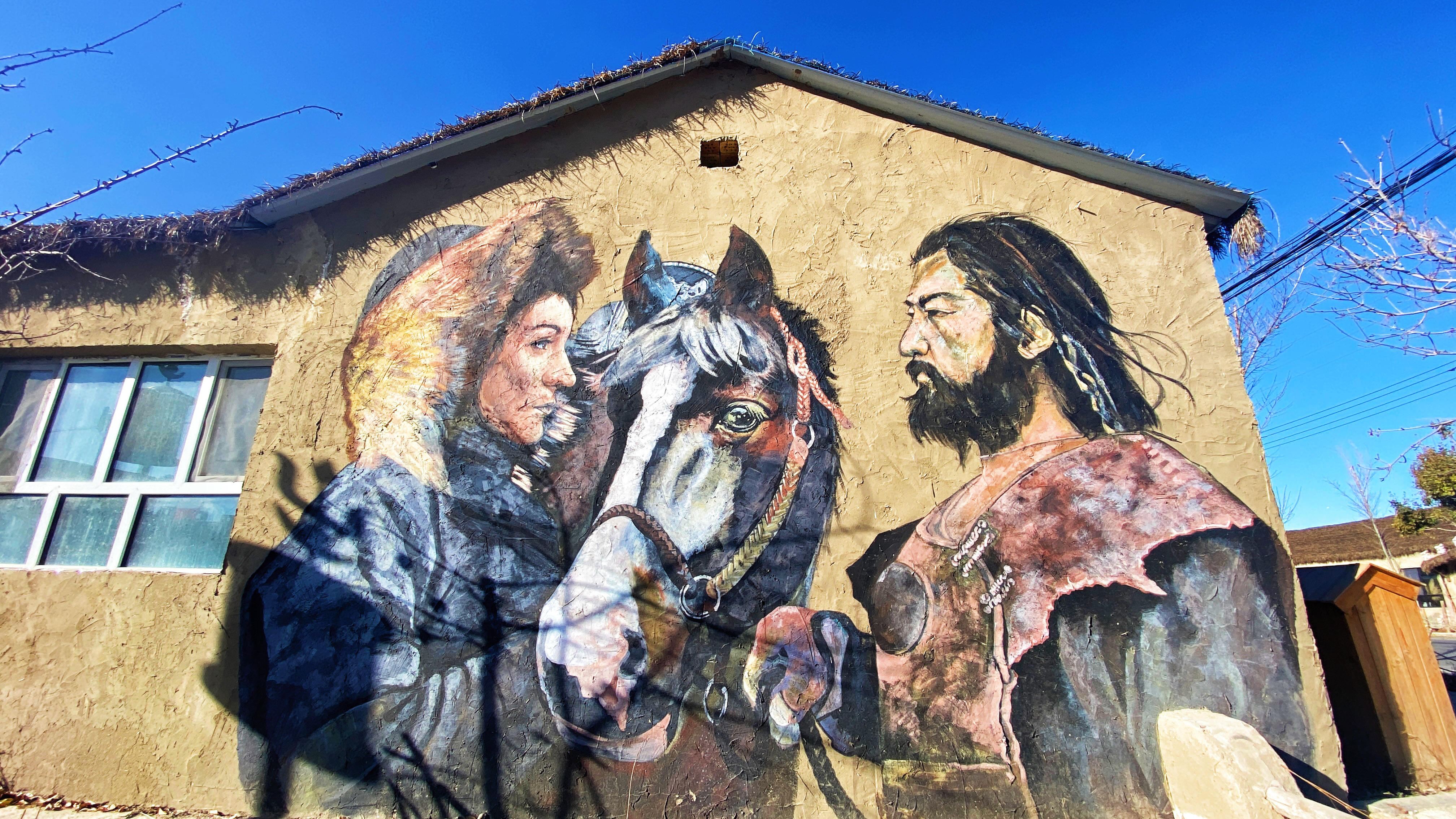 A village building is decorated with a mural reflecting the cultures of Bogdal Village, Xinjiang. /CGTN
