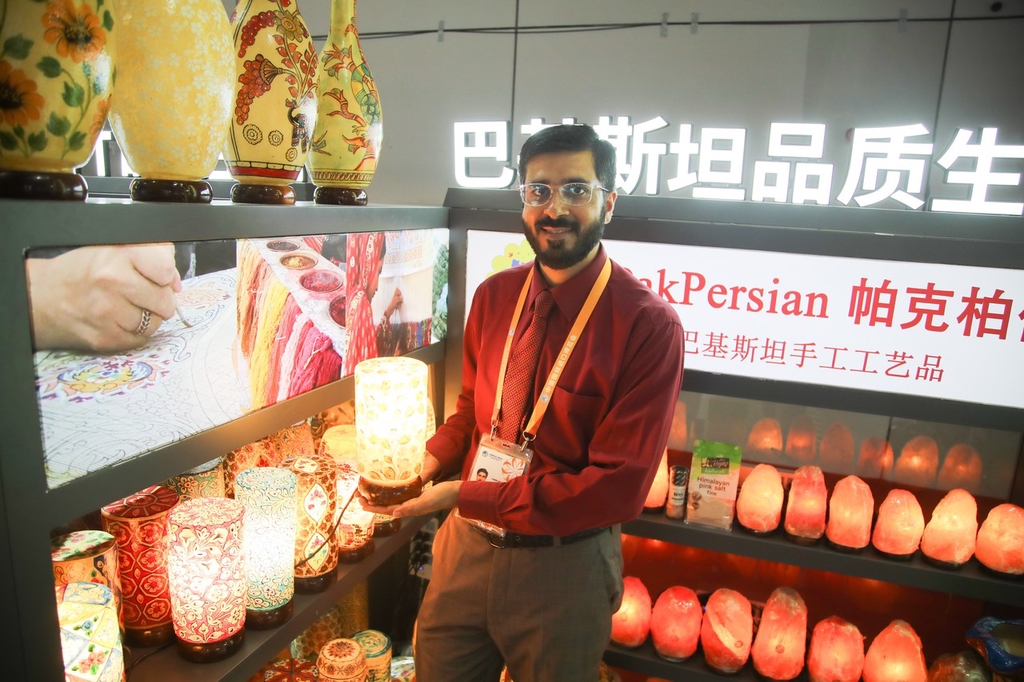 A stall staff member shows visitors crafts from Pakistan, including camel skin lamps, on November 5, 2023, at the China International Import Expo in Shanghai. /IC