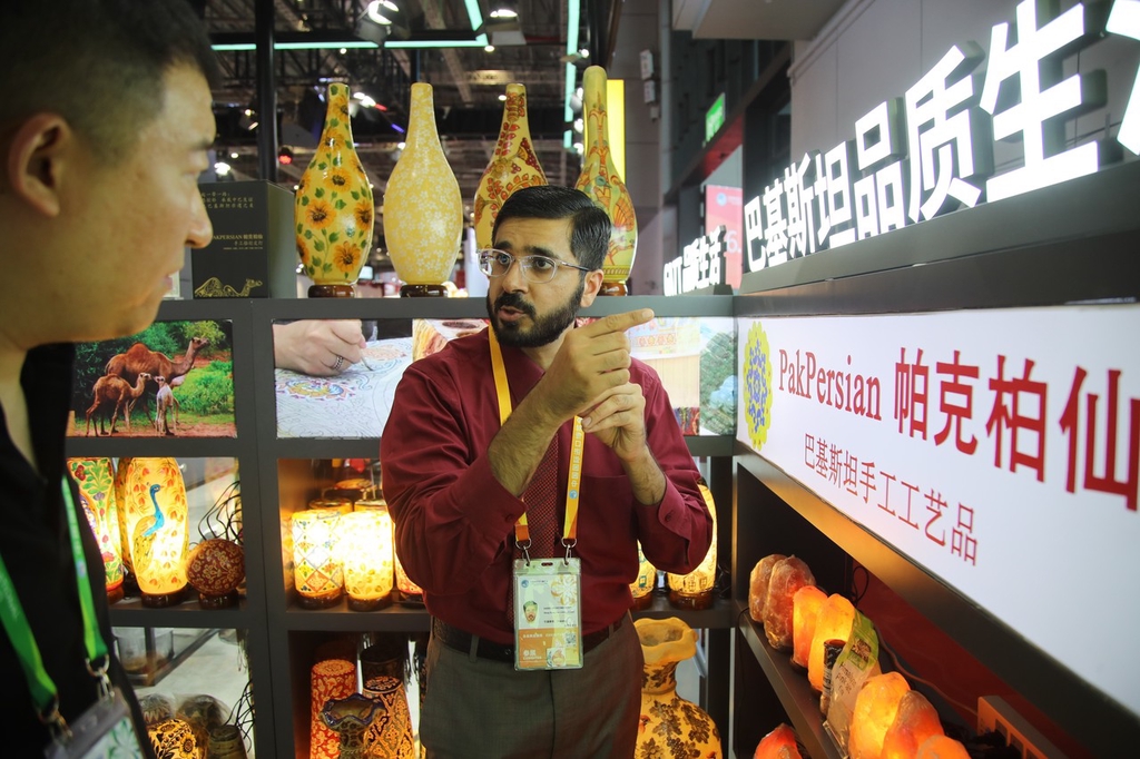 A stall staff member shows visitors crafts from Pakistan, including camel skin lamps, on November 5, 2023, at the China International Import Expo in Shanghai. /IC