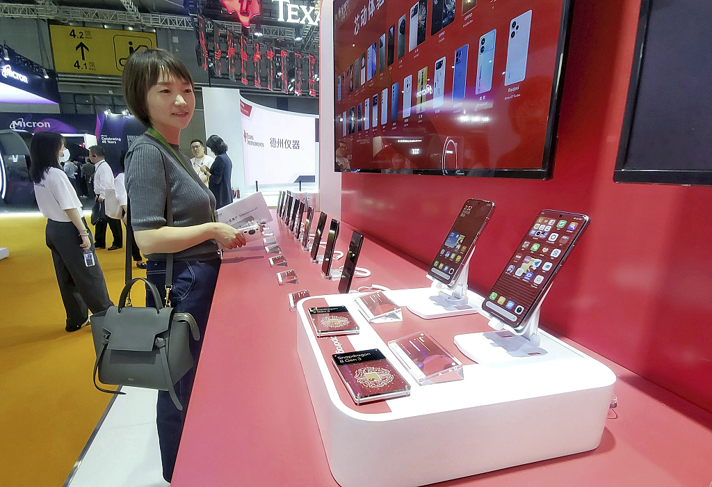 A photo taken on November 6, 2023 shows a visitor taking a look at smartphones equipped with the most advanced chips displayed at the 6th China International Import Expo in Shanghai, China. /CFP