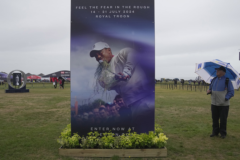 A spectator looks at a poster for the British Open 2024, featuring a picture of Tiger Woods, as he walks at the Royal Liverpool Golf Club in Hoylake, England, July 18, 2023. /CFP