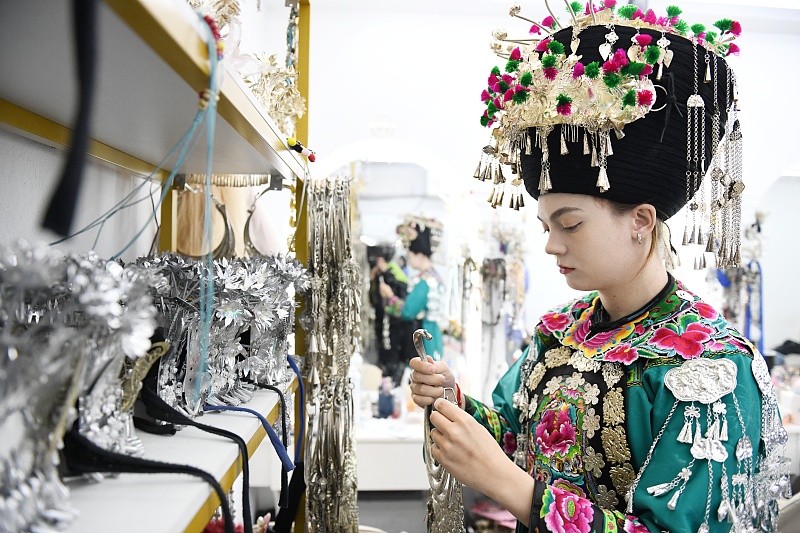 A Russian woman dressed in traditional Miao costume admires the beauty of Miao silverware in Fenghuang County, Hunan Province, November 10, 2023. /CFP