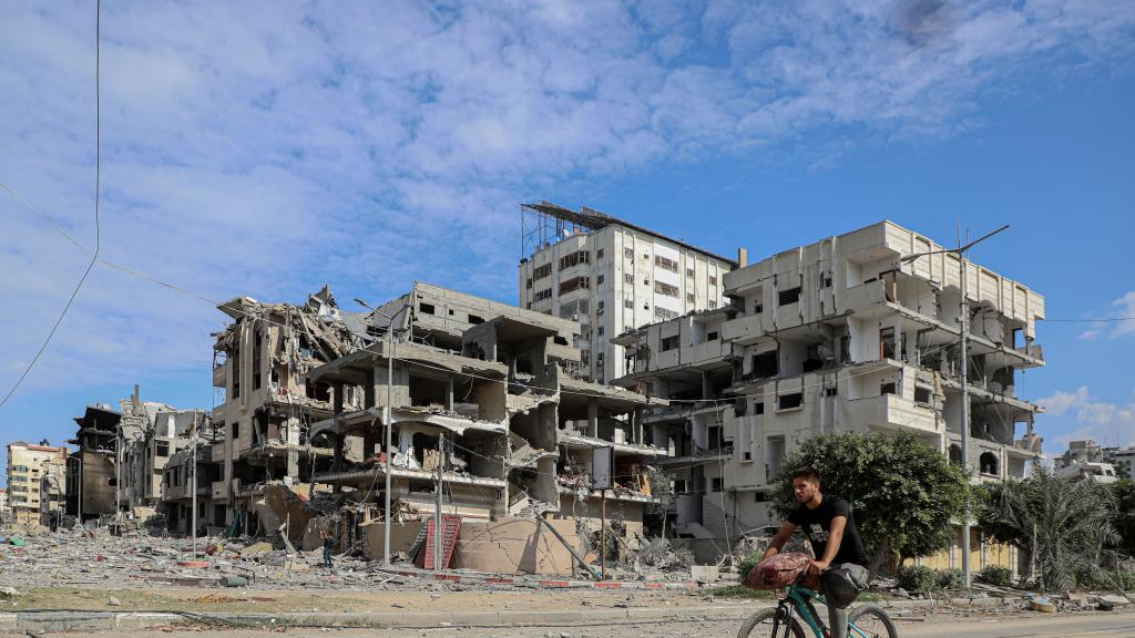 A man rides a bike near buildings destroyed in Israeli airstrikes in Gaza City, October 17, 2023. /Xinhua