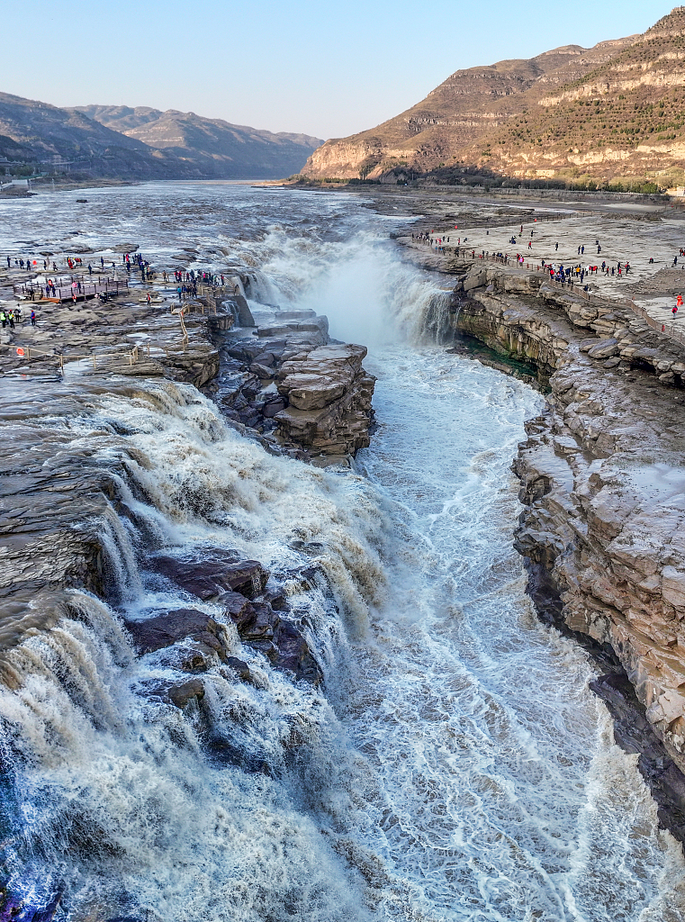 A photo taken on November 14, 2023 shows people admiring the majestic views of the Hukou Waterfall in Yan'an City, Shaanxi Province. China. /CFP