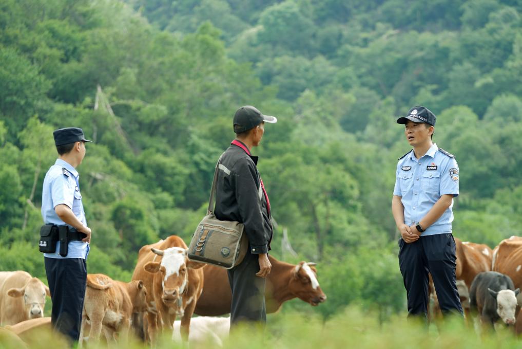Ma Ming(R), police officer, talking with local resident. /Xinhua