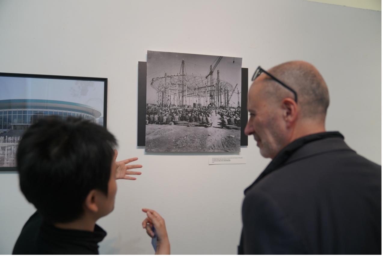 A photo shows two visitors looking at images of the Shanghai Indoor Stadium displayed at an exhibition in Barcelona, Spain. /Photo provided to CGTN