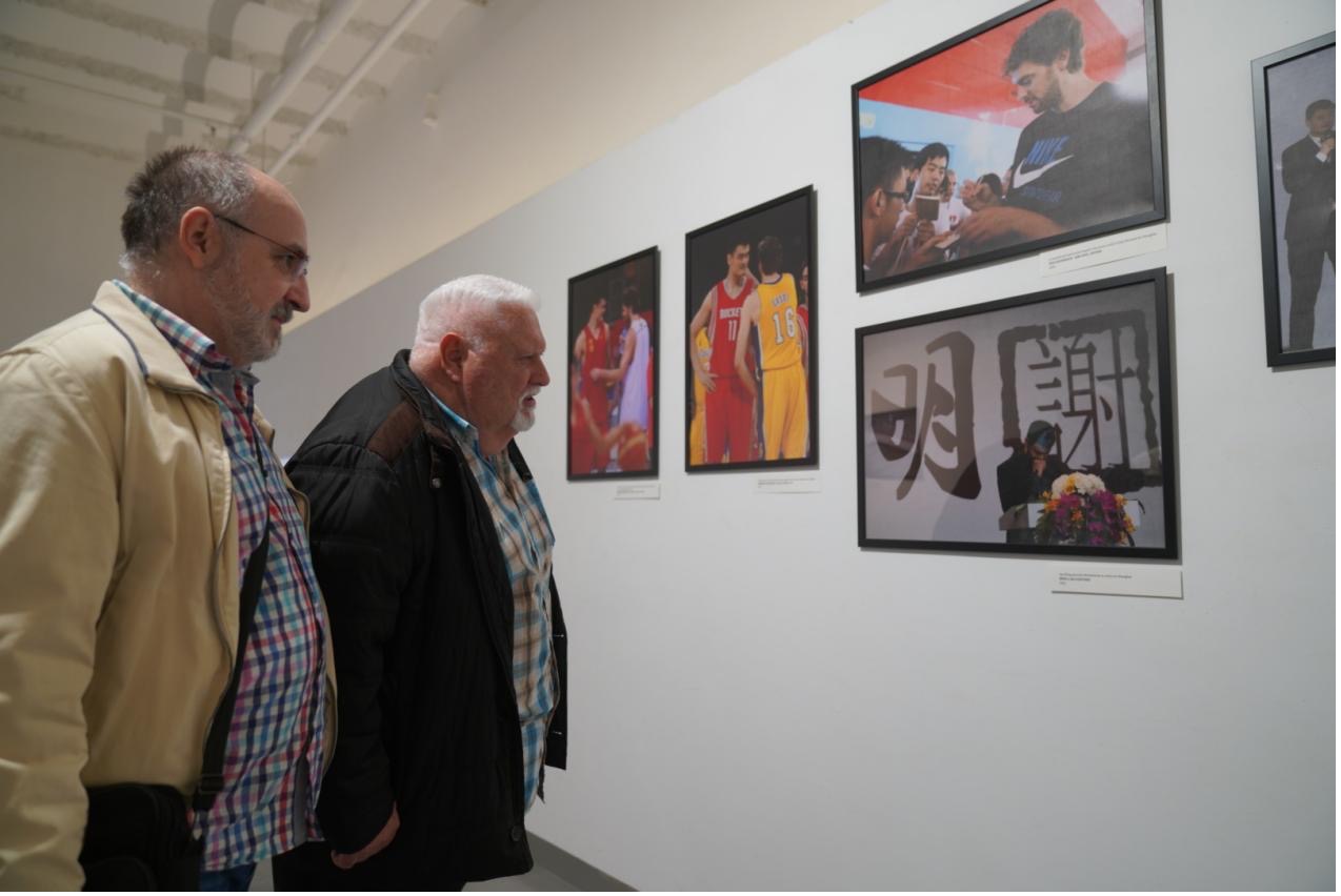 A photo shows two visitors looking at images of basketball players Pau Gasol and Yao Ming displayed at an exhibition in Barcelona, Spain. /Photo provided to CGTN