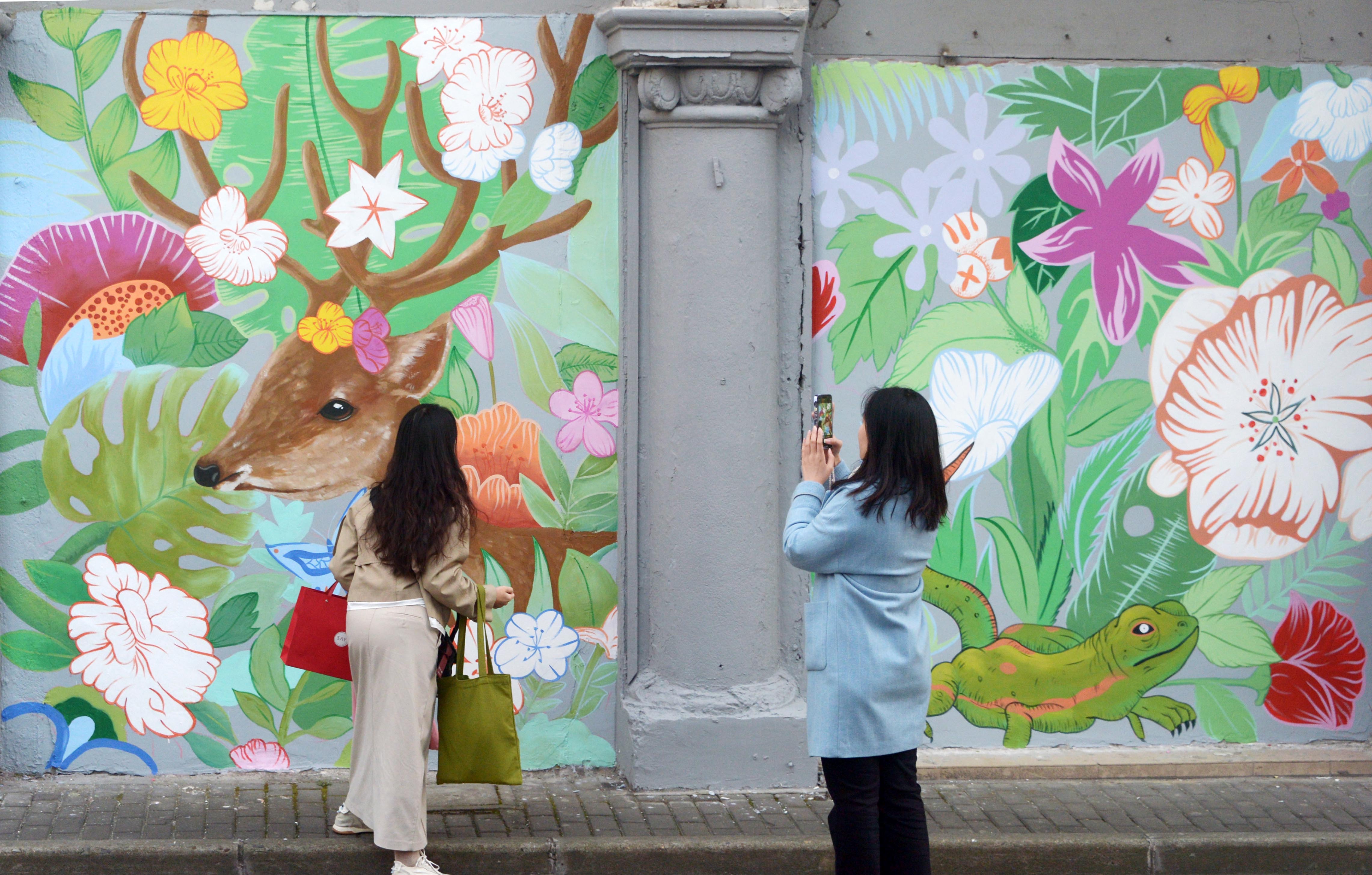 A woman snaps photos with the freshly decorated murals on Fangbang Middle Road in Shanghai on November 18, 2023. /IC