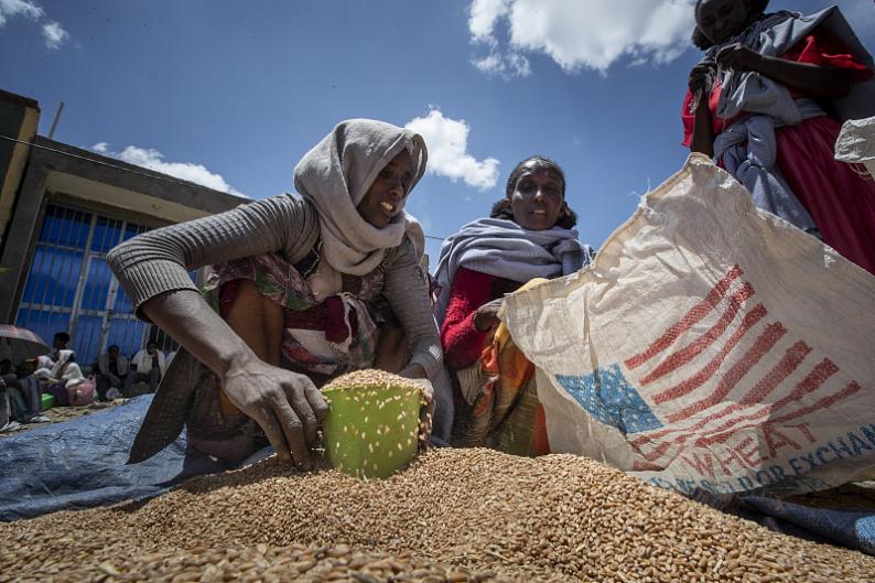 An Ethiopian woman scoops up portions of wheat to be allocated to each waiting family after it was distributed by the Relief Society of Tigray in the town of Agula, in the Tigray region of northern Ethiopia, May 8, 2021. /CFP