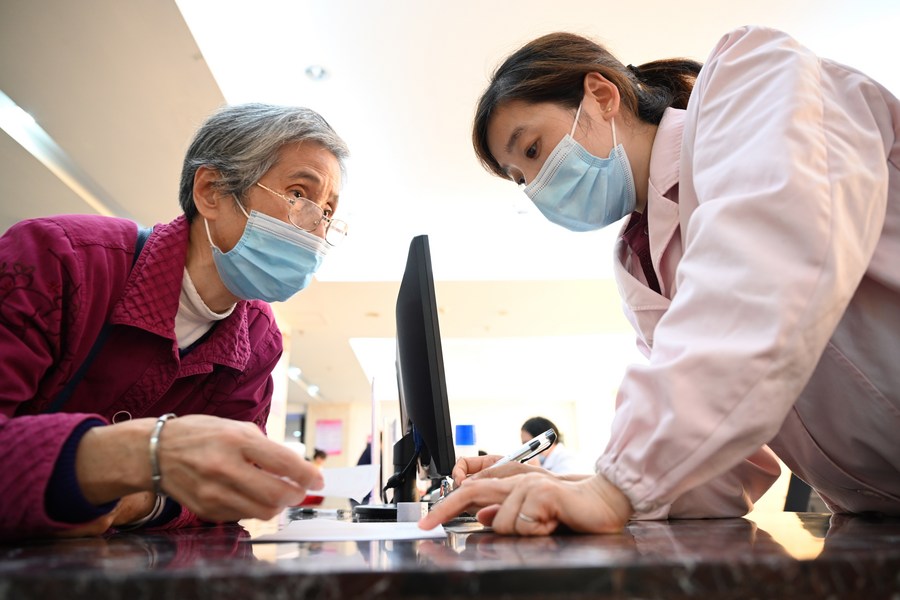 A staff member explains medical insurance policies to a resident at a hospital in Sanming City, southeast China's Fujian Province, November 18, 2020. /Xinhua