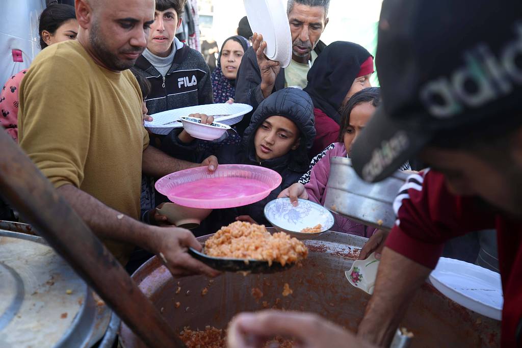 Displaced Palestinians wait in line as volunteers cook a meal in Dair El-Balah in the Gaza Strip, November 23, 2023. /CFP