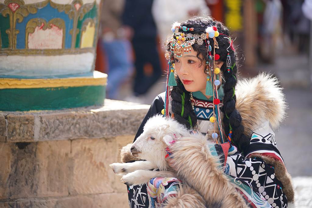 A tourist in a traditional Chinese costume poses for a photo in Diqing Tibetan Autonomous Prefecture, southwest China's Yunnan Province, on February 19, 2023. /CFP