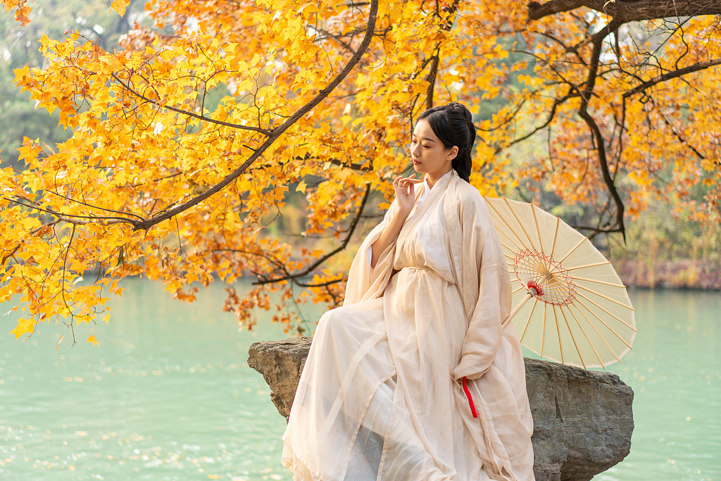 A tourist in a traditional Chinese costume poses for a photo at the Summer Palace in Beijing, on November 6, 2022. /CFP
