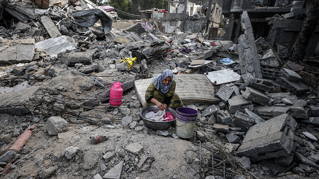 A Palestinian woman washes clothes as her family continue their daily lives among the rubble and debris of their family house destroyed by Israeli attacks in Deir al Balah, Gaza, November 25, 2023. /CFP