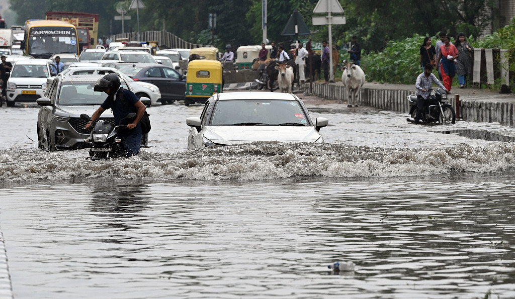 Commuters wade along a waterlogged road near Vinod Nagar after sudden rain in New Delhi, India, September 23, 2023. /CFP