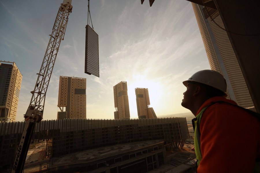 A worker monitors as a giant piece of glass is lifted before being installed as part of the glass curtain walls of a building in the CBD of Egypt's new administrative capital, November 24, 2023. /Xinhua