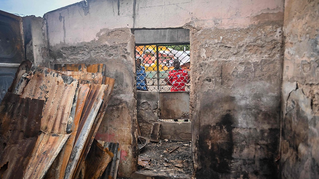 Men look through the window of a burnt-out house near Fontaine Hospital, now closed after an armed attack in the Cité Soleil district of Port-au-Prince, Haiti, November 18, 2023. /CFP